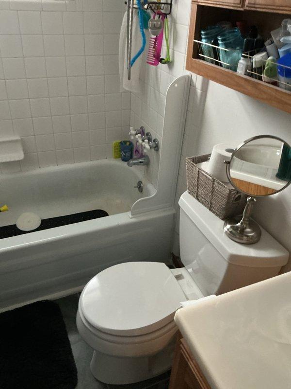 Completed complimentary whole home plumbing inspection, focusing on bathroom and utility closet areas. Inspected bathroom fixtures including tub, shower, and toilet for proper function and potential leaks. Examined water heater installation and PVC drain pipe configuration in utility closet, noting current condition and identifying any maintenance needs. Photos documented all inspected components for reference.