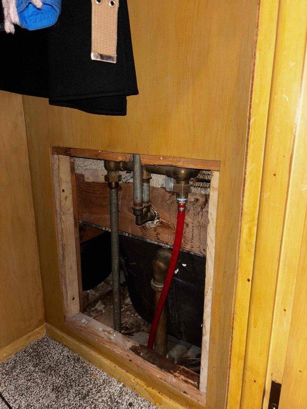 Accessed plumbing behind wall panel to diagnose slow draining tub. Inspected drain line configuration and cleared blockage causing drainage issue. System now operating properly with normal flow restored.