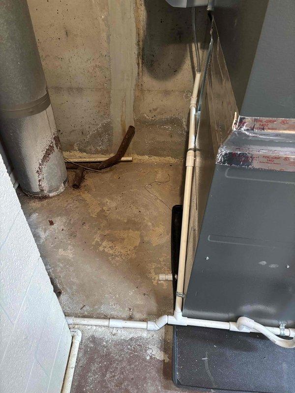 Completed installation of new furnace system with proper condensate drainage setup. Installed white PVC drainage pipes with appropriate elbows and connections to ensure proper water removal. System includes metal cabinet housing with sealed panels and copper line connections mounted on drain pan for added protection.