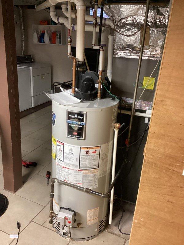 Identified and repaired water leak originating from failed seal on water heater supply pipe connection. Inspected basement floor area affected by slow leak spread, confirmed no damage to surrounding tile flooring, and verified proper function of Defender water heater system after repair.