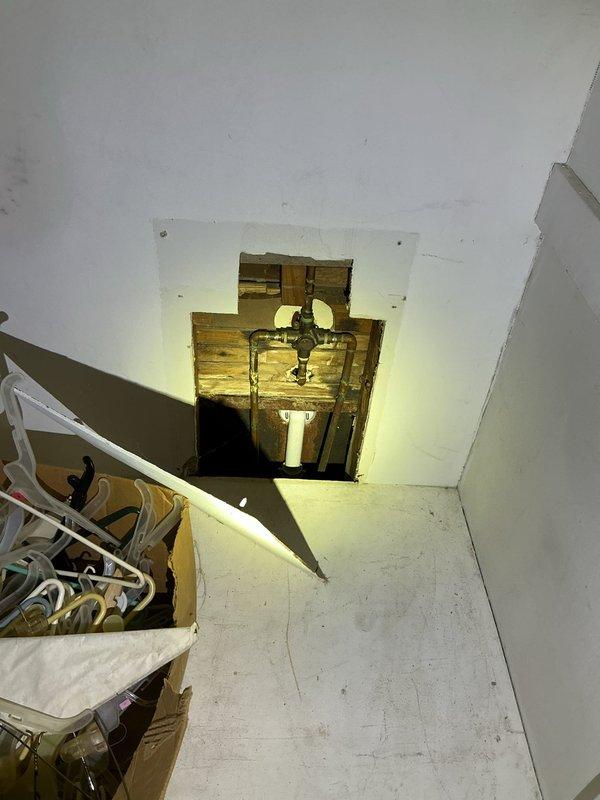 Accessed wall cavity to repair non-functioning shower faucet. Removed rectangular drywall section to expose aged copper piping and valve assembly. Successfully replaced faulty valve, restoring proper shower operation.