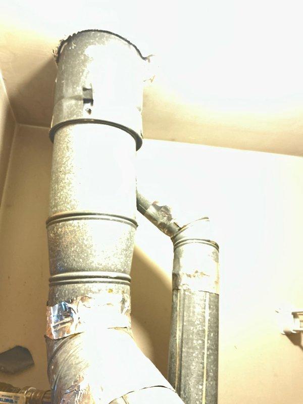 Conducted furnace replacement estimate for a 58-year-old Bard system with customer request for AC attachment. Inspected existing ductwork, noting aged galvanized steel ducts with visible wear at connection joints and previous tape repairs. Evaluated utility closet layout containing a Rheem Performance water heater adjacent to the current HVAC unit, with limited space considerations and insulated ductwork requiring assessment for compatibility with new system.