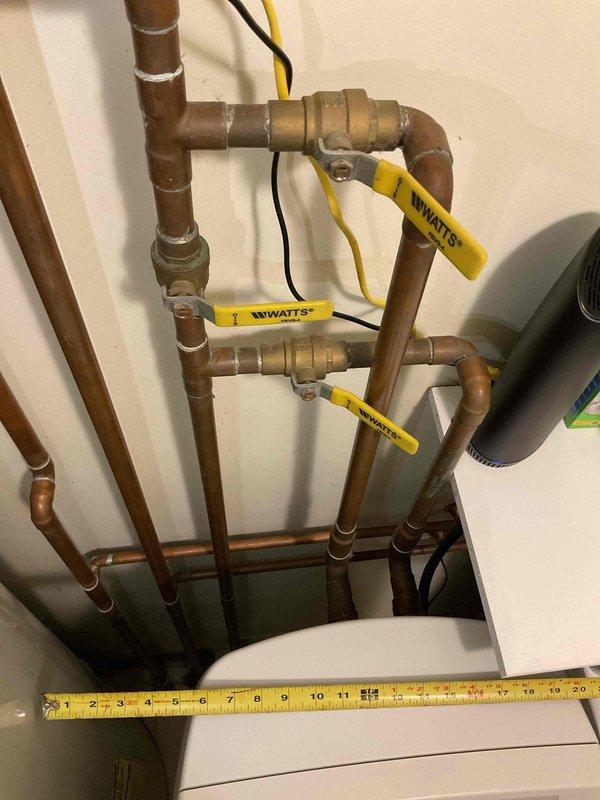 Completed water heater estimate for CWOW customer in confined utility space. Assessed existing aging blue cylindrical water heater with copper piping showing signs of wear and mineral deposits. Evaluated Watts valve system and measured clearances to determine appropriate replacement options considering the limited installation area.