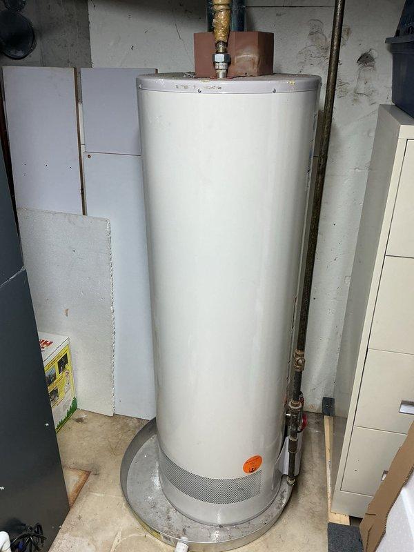 Conducted an estimate for tankless water heater replacement, evaluating the existing cylindrical unit located in utility area. Documented current installation, including copper piping, brass fittings, and ventilation requirements. Noted Club Membership status valid through May 2026. Photos captured both the current water heater setup and surrounding utility space with exposed structural elements to facilitate accurate quote preparation.