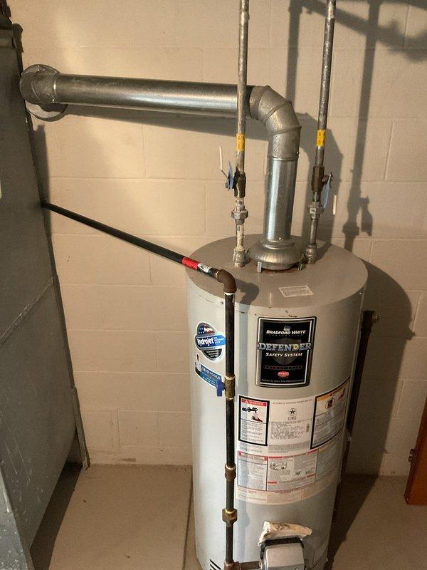 Conducted site inspection for PEX repipe estimate, documenting existing plumbing infrastructure in unfinished basement area with exposed wooden joists and concrete block walls. Evaluated Bradford White Defender Safety System water heater installation, noting current connection points, supply lines, and ventilation system to determine integration requirements for proposed repiping project.