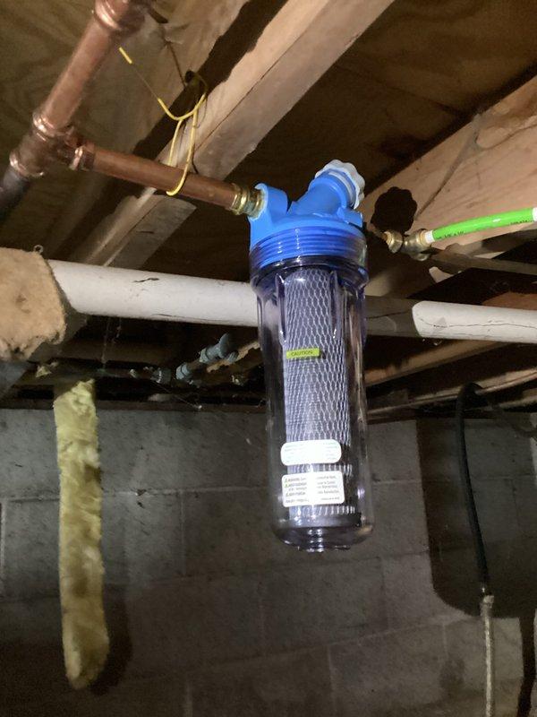 Installed a whole-house water filter system in the crawlspace, connecting it to the existing copper supply line. The clear housing with blue cap was properly mounted and secured to ensure effective filtration of sediment and contaminants from the incoming water supply.