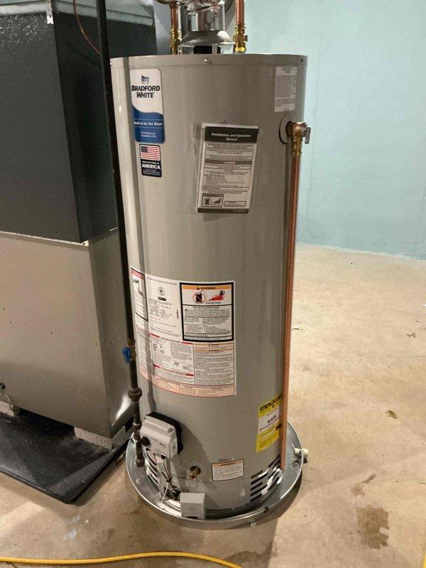 Successfully installed a 50-gallon Bradford White natural gas water heater with 6-year warranty (ND 6/1 model) in basement utility area. Completed all necessary copper pipe connections at the top of the unit and properly connected the gas valve assembly. Water heater was installed according to manufacturer specifications with appropriate plumbing connections.