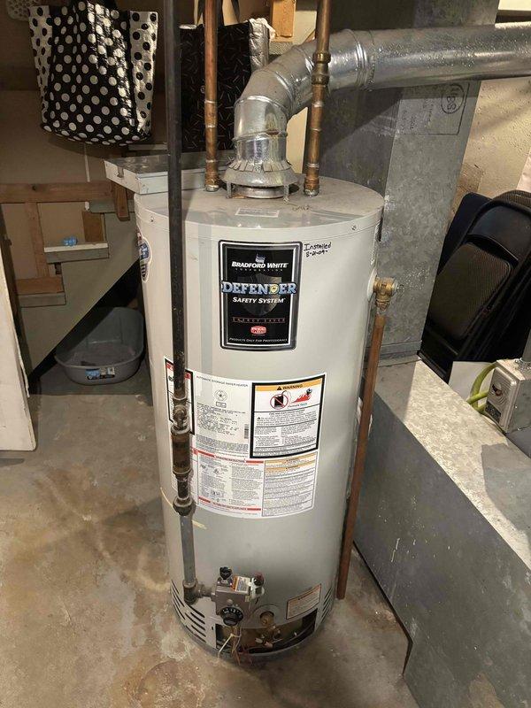 Inspected 14-year-old Bradford White water heater (2009 installation) due to customer complaint of shortened hot water availability during showers. Visual examination revealed aging unit with standard wear. Recommended replacement due to unit age and declining performance rather than repair, as efficiency and reliability will continue to deteriorate.