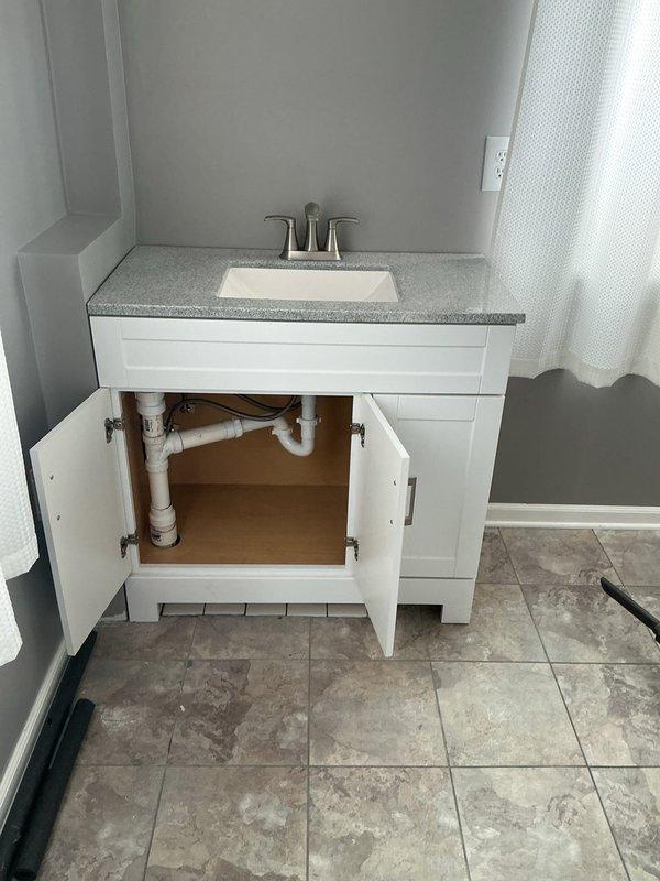 Successfully completed bathroom group water line relocation as part of two-day CWOW plumbing project. Installed new PVC drain assembly with P-trap and properly secured water supply lines beneath both bathroom vanity and kitchen sink. All connections were verified for proper function with no leaks observed.