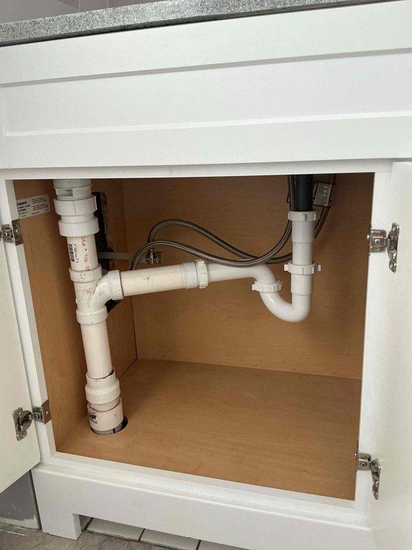 Successfully completed bathroom group water line relocation as part of two-day CWOW plumbing project. Installed new PVC drain assembly with P-trap and properly secured water supply lines beneath both bathroom vanity and kitchen sink. All connections were verified for proper function with no leaks observed.