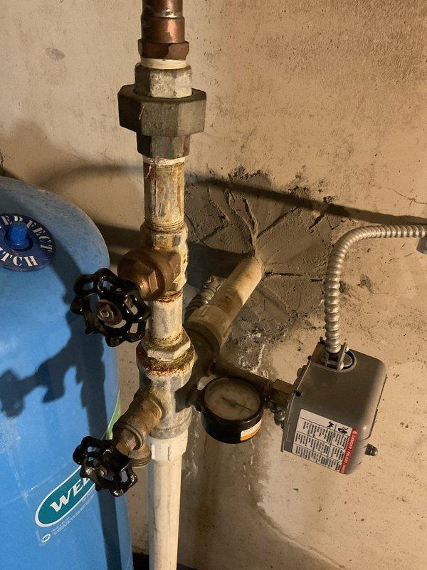 Identified water intrusion at foundation penetration point where well water line and electrical conduit enter basement. Observed significant wall deterioration with mineral deposits and staining. Confirmed leak stops when well pump is turned off and system pressure is released. Inspected pressure tank assembly and control components for potential repair options without excavation.