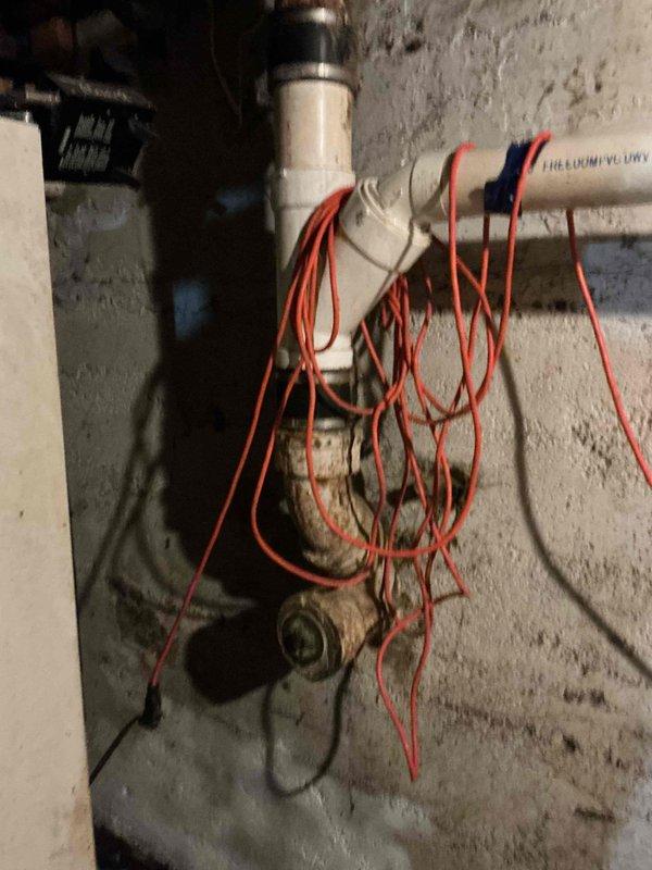Responded to a main drain backup call. Inspected the plumbing system in the basement area, which included PVC drain pipes with a brass valve showing signs of corrosion. Cleared the blockage in the 3.25" Freedom Flow drain line, restoring proper drainage function.