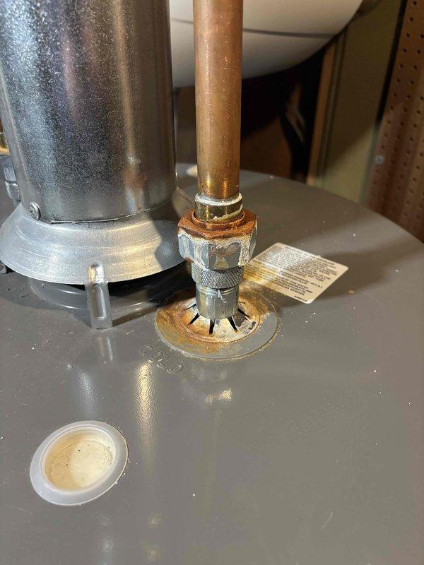 Responded to water heater leak service call. Inspection revealed corrosion at copper pipe connection to tank fitting, with visible oxidation at the joint. Replaced damaged connection components to resolve active leak.