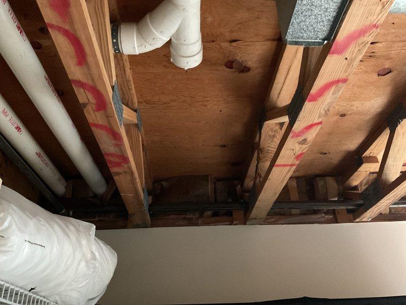 Completed site assessment for gas line installation to accommodate client's dryer. Inspection of the utility area revealed exposed ceiling structure with wooden joists and existing PVC plumbing lines. Documented current conditions with photos, including utility area layout and ceiling access points marked with construction indicators, to facilitate accurate project estimation.