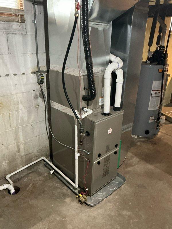 Conducted site assessment for replacement condenser at single-family residence with existing 3-year-old AC system. Inspected basement utility area containing furnace unit with connected PVC drain pipes and flexible ductwork, adjacent water heater, and examined ceiling structure with exposed joists and insulated ducting. Documented current installation configuration and measurements to prepare accurate quote for new condenser installation.