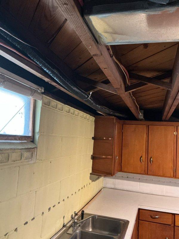 Conducted site assessment for replacement condenser at single-family residence with existing 3-year-old AC system. Inspected basement utility area containing furnace unit with connected PVC drain pipes and flexible ductwork, adjacent water heater, and examined ceiling structure with exposed joists and insulated ducting. Documented current installation configuration and measurements to prepare accurate quote for new condenser installation.