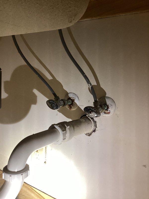 Conducted PCI-Plumbing Club Inspection on bathroom fixtures. Verified proper installation of dual water supply lines with shut-off valves and PVC drain pipe configuration. Noted minor mineral buildup at wall connection points and examined sink faucet assembly with transparent handle and brass drain stopper.
