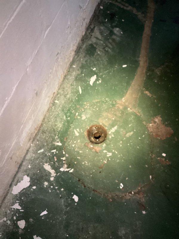 Responded to emergency call regarding suspected sewage backup through basement floor drain. Upon inspection, identified significant deterioration around floor drain with visible sediment buildup and water damage. Cleared blockage in drain line and verified proper drainage function to resolve backup issue.