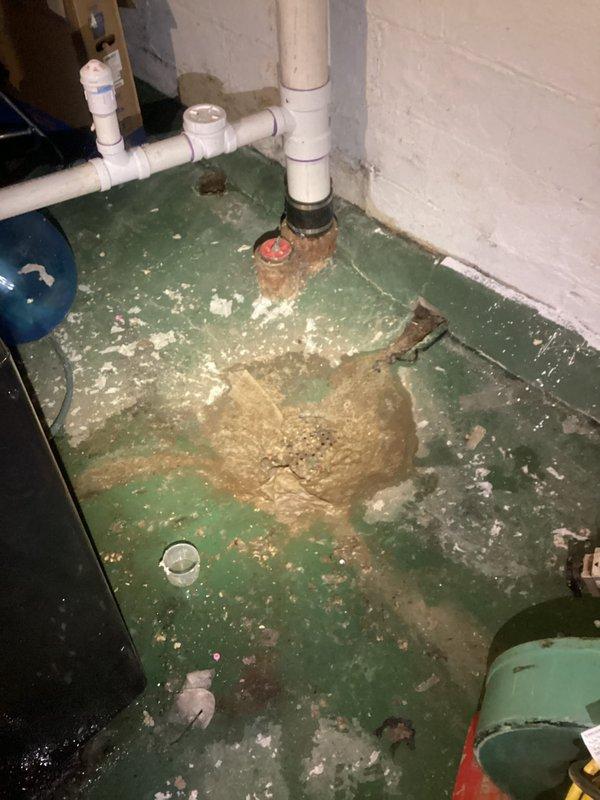 Responded to emergency call regarding suspected sewage backup through basement floor drain. Upon inspection, identified significant deterioration around floor drain with visible sediment buildup and water damage. Cleared blockage in drain line and verified proper drainage function to resolve backup issue.