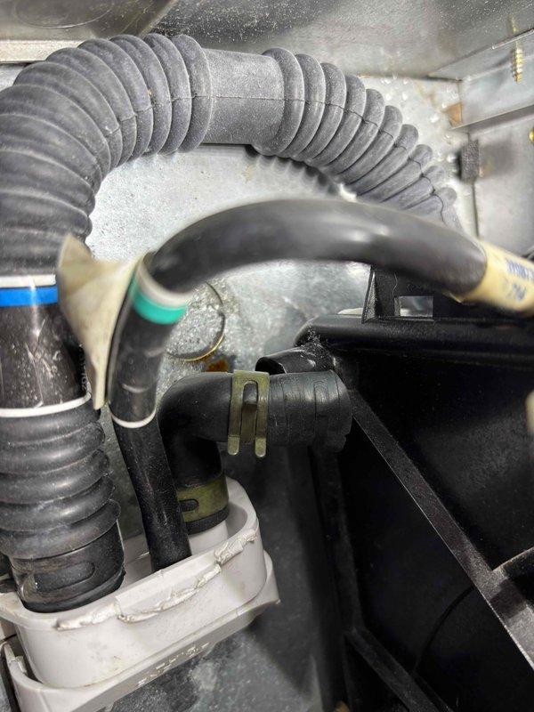 Responded to water leak issue on 17-year-old CAR furnace. Discovered condensate drain tube misalignment with collection pan, causing water to leak underneath unit. Repositioned drain tube according to "THIS END UP" directional indicators and verified proper drainage path through the black corrugated discharge hose with green connector ring. System now operating correctly with no further leakage.