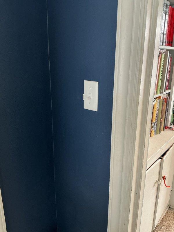 Relocated electrical outlet per customer request in residential setting. Worked with existing outlet positioned near bookshelf area, moving it to the specified location on navy blue wall. Completed installation with proper mounting and verified functionality after relocation.