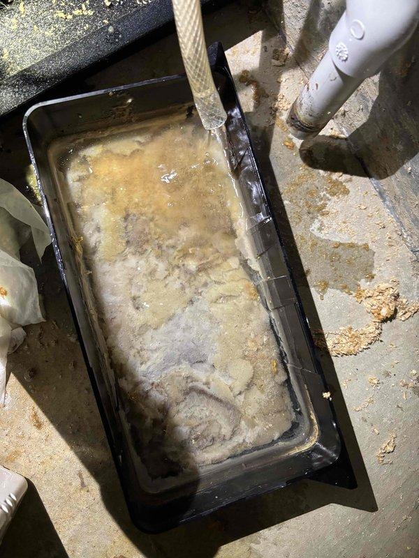 Responded to service call for 2-year-old unit not producing heat with water leakage. Discovered significant sludge and sediment buildup in the condensate drain pan causing blockage and water overflow. Cleaned drain pan, cleared clogged copper condensate line showing oxidation, and restored proper system operation.