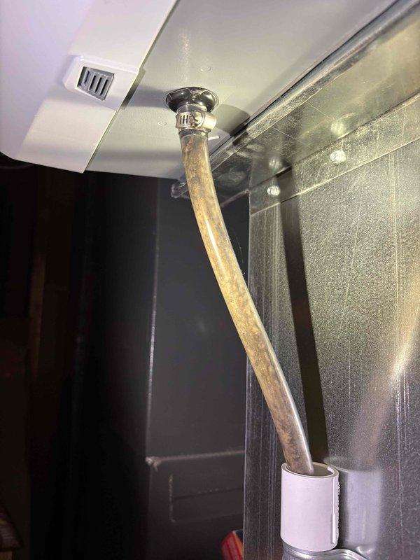 Responded to service call for 2-year-old unit not producing heat with water leakage. Discovered significant sludge and sediment buildup in the condensate drain pan causing blockage and water overflow. Cleaned drain pan, cleared clogged copper condensate line showing oxidation, and restored proper system operation.