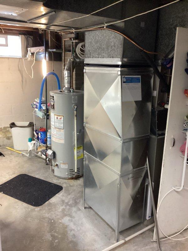 Conducted on-site water heater estimate for replacement of 40-gallon tank unit showing active leakage and rust deterioration at bottom. Documented existing installation with photos showing current water heater setup and HVAC placement in utility area with PEX connections and surrounding ductwork to assist with proper replacement specifications.