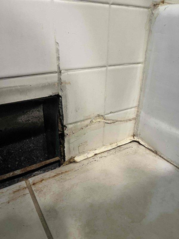 Conducted inspection of 1950s residential bathroom requiring replacement of outdated two-stem shower faucet with modern single valve system. Documented significant water damage to wall tiles and underlying structure, with visible deterioration at tile-floor junction and evidence of moisture penetration. Estimate prepared for complete valve replacement including necessary tile cutting, installation of remodel plate, and addressing associated water damage in the confined plumbing access area.