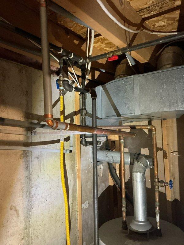 Conducted a furnace replacement estimate for a recently purchased home, documenting the existing HVAC setup with photos of the utility area showing exposed ductwork, gas lines, and adjacent water heater installation. Evaluation included assessment of current basement mechanical configuration with copper plumbing, flexible gas lines, and existing ductwork to determine appropriate furnace sizing and installation requirements.