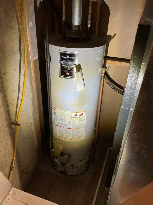 Conducted a furnace replacement estimate for a recently purchased home, documenting the existing HVAC setup with photos of the utility area showing exposed ductwork, gas lines, and adjacent water heater installation. Evaluation included assessment of current basement mechanical configuration with copper plumbing, flexible gas lines, and existing ductwork to determine appropriate furnace sizing and installation requirements.