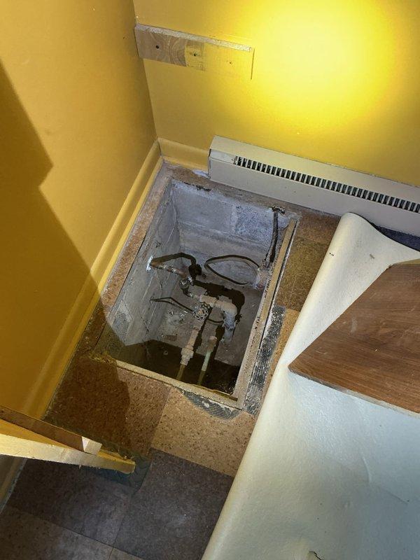 Performed site assessment for water heater and water softener estimate. Inspected existing utility access point in floor containing aged plumbing components. Evaluated installation space requirements in yellow-walled room with consideration for proper ventilation and access requirements. Documented current conditions with photos for accurate system specification and quote preparation.