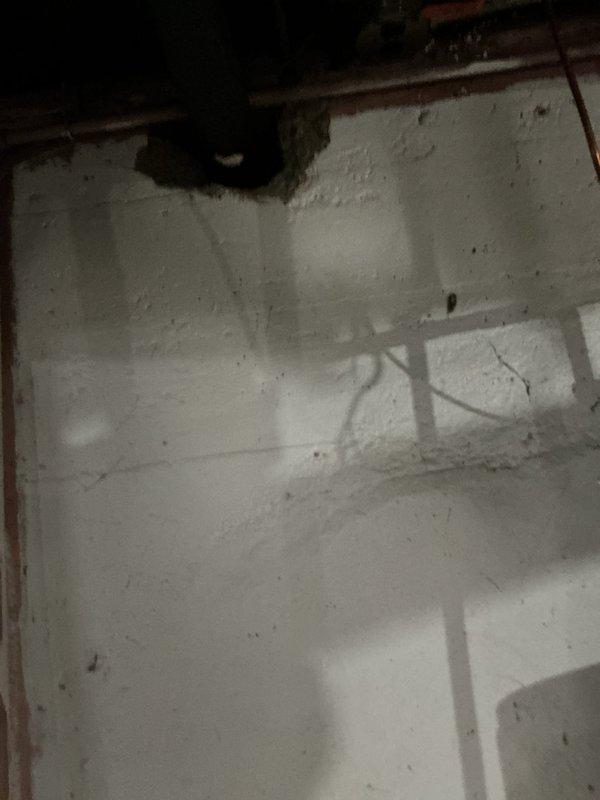 Responded to service call for bathroom backup issues affecting shower and toilet. Visual inspection revealed damaged wall section near plumbing and accessed basement to examine drainage system. Located blockage in main drain line serving bathroom and cleared obstruction, restoring proper drainage function for disabled resident's essential facilities.