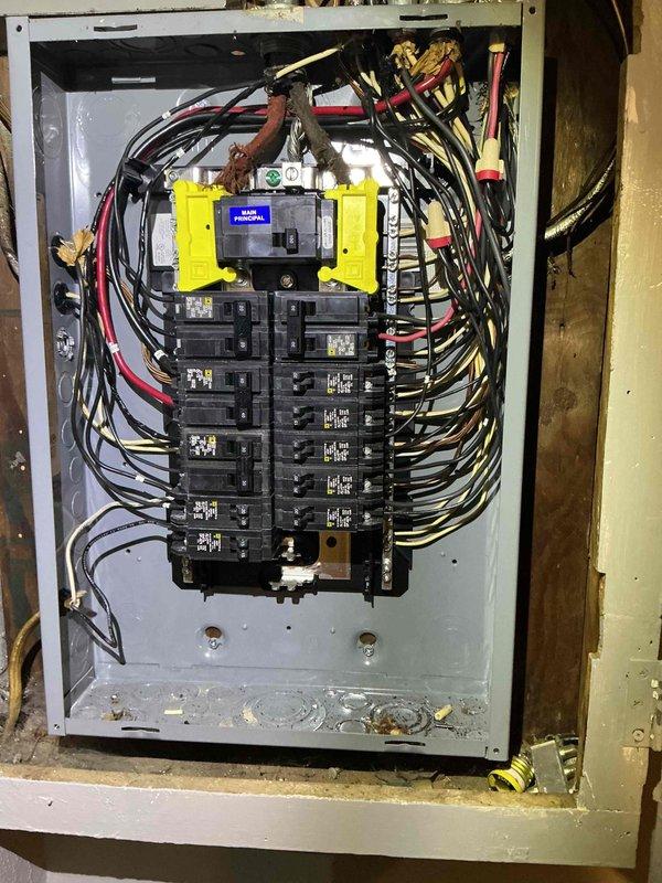 Performed comprehensive ECI inspection of electrical panel, documenting main breaker condition and circuit organization. Observed standard yellow-encased main breaker with multiple circuit breakers arranged in dual columns, with appropriate black, red, and white wiring connections throughout. Noted minor dust accumulation at panel bottom requiring routine maintenance.
