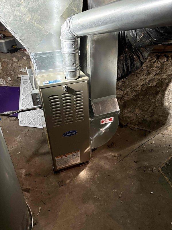 Successfully installed new Carrier furnace system in basement utility area, properly connecting unit to existing circular metal ductwork with appropriate elbow joints. Completed all necessary connections and verified proper operation of the system prior to finalizing installation paperwork.