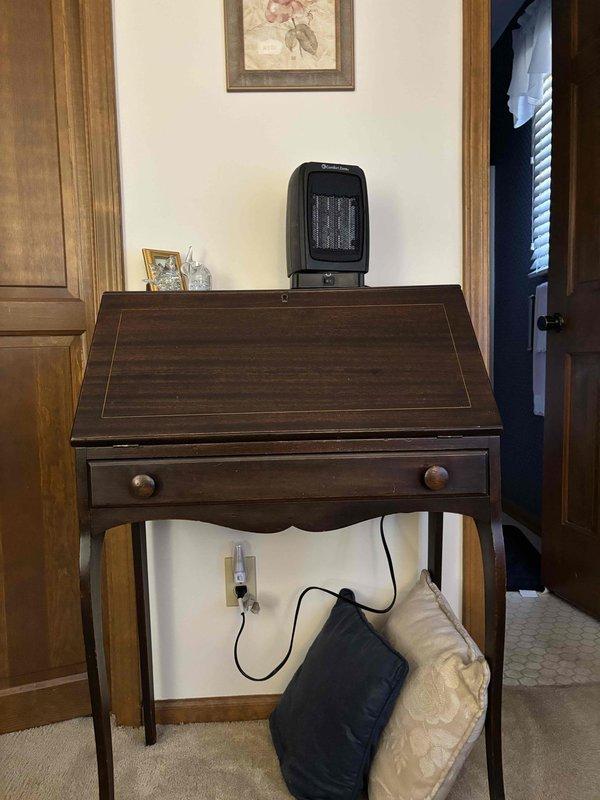 Delivered and positioned portable space heater for client as requested. Heater was placed in two locations for client review - initially on a wooden secretary desk near wall outlet and alternatively on brick fireplace hearth adjacent to side table. Verified unit was functioning properly and power cord was safely positioned to prevent tripping hazards.