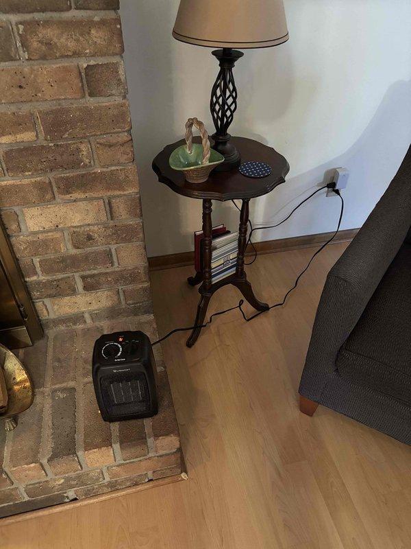 Delivered and positioned portable space heater for client as requested. Heater was placed in two locations for client review - initially on a wooden secretary desk near wall outlet and alternatively on brick fireplace hearth adjacent to side table. Verified unit was functioning properly and power cord was safely positioned to prevent tripping hazards.