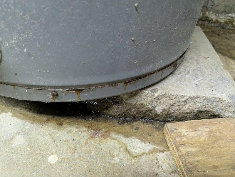 Responded to service call for 12-year-old water heater not producing hot water. Upon inspection, found significant corrosion at tank base and evidence of moisture damage/mold at installation point. Determined unit had reached end of useful life due to tank deterioration and recommended replacement.