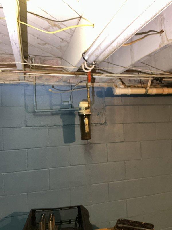 Diagnosed kitchen sink dual-basin drainage issue where water backed up into adjacent sink during drain use. Inspection revealed aged P-trap assembly with corrosion at sink connection and deteriorated wall area around drain exit point. Also identified leaking water supply valves at washer connection in basement requiring replacement.