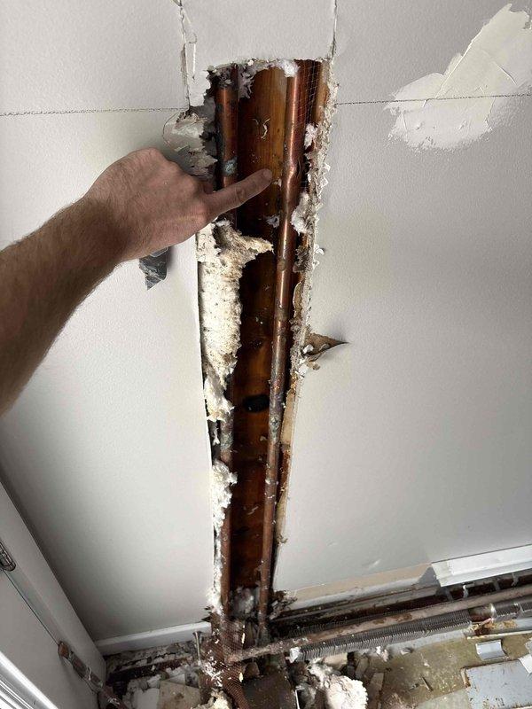 Inspected 30-year-old non-functioning radiant heat system. Located and accessed copper supply lines through drywall to diagnose issue. Visual inspection revealed deteriorated copper piping within the wall cavity requiring repair to restore system functionality.