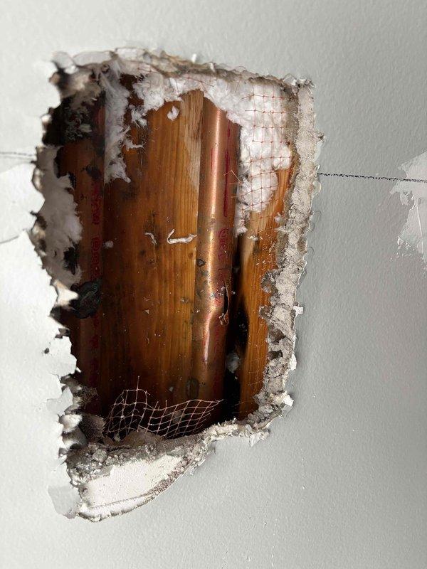 Inspected 30-year-old non-functioning radiant heat system. Located and accessed copper supply lines through drywall to diagnose issue. Visual inspection revealed deteriorated copper piping within the wall cavity requiring repair to restore system functionality.