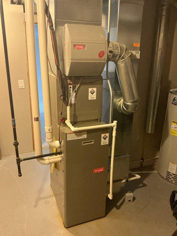 Completed comprehensive evaluation of existing Bryant HVAC system located in basement utility room. System includes furnace with attached humidifier, PVC drainage pipes, and metal ductwork throughout the space. Documented current installation configuration and ductwork layout to prepare accurate replacement estimate for new furnace and AC units as requested.