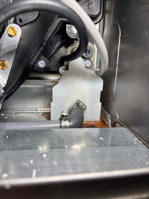 Inspected unit previously serviced in November for reported leak. Identified condensate trap reservoir with moisture accumulation and signs of oxidation at bottom of compartment. Verified connections and hose clamps securing the drain line to prevent further water leakage. System now operating properly.