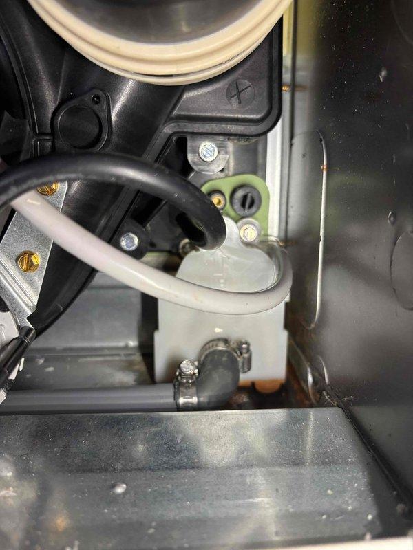 Inspected unit previously serviced in November for reported leak. Identified condensate trap reservoir with moisture accumulation and signs of oxidation at bottom of compartment. Verified connections and hose clamps securing the drain line to prevent further water leakage. System now operating properly.