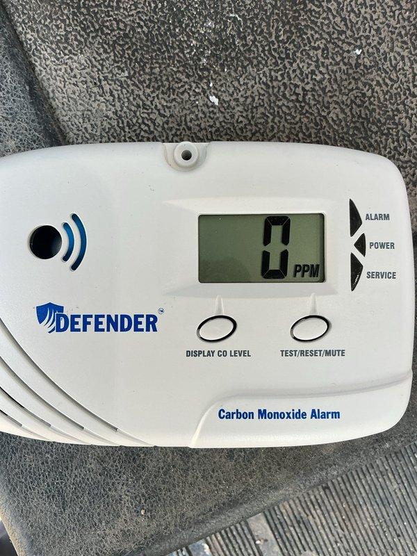 Responded to CO alarm activation for a visually impaired client. Upon inspection, found the Defender carbon monoxide detector displaying "End" message indicating end-of-life status. Replaced the expired unit with new detector which is now functioning properly, showing "0 PPM" reading. Client educated on proper CO alarm maintenance and replacement schedule.