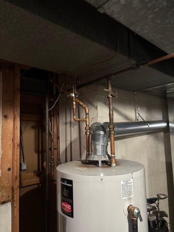 Conducted a comprehensive assessment of a 45-year-old residence for water heater replacement. Evaluated existing unit located in basement utility area, which features copper supply lines, brass valves, galvanized metal venting, and connections to home's plumbing system. Photos documented current installation configuration against concrete block walls for accurate replacement specifications.