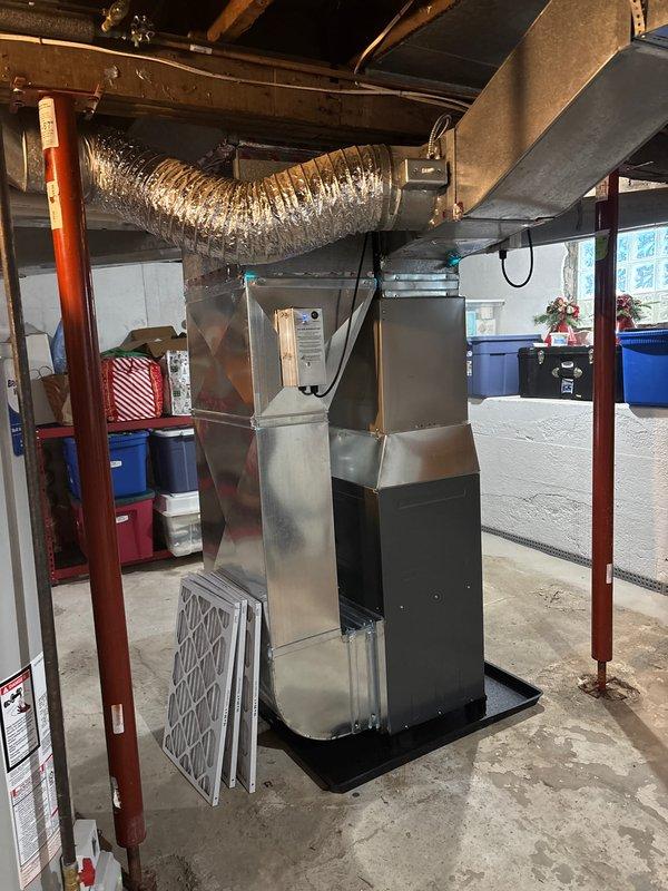 Successfully installed new furnace unit in basement utility area, mounting system on black base pan with proper connection to existing ductwork. Set up condensate drain system with PVC P-trap configuration to prevent sewer gas infiltration, and provided replacement air filters for ongoing maintenance.