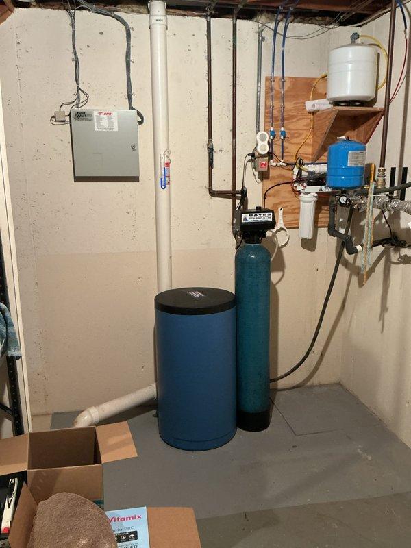 Successfully installed a water softener system in the utility room, integrating it with the existing plumbing infrastructure. The installation included connecting the blue cylindrical water softener tank and filtration tank to the home's water supply using appropriate copper and PVC piping. All connections were properly secured and tested to ensure optimal system performance with no leaks.