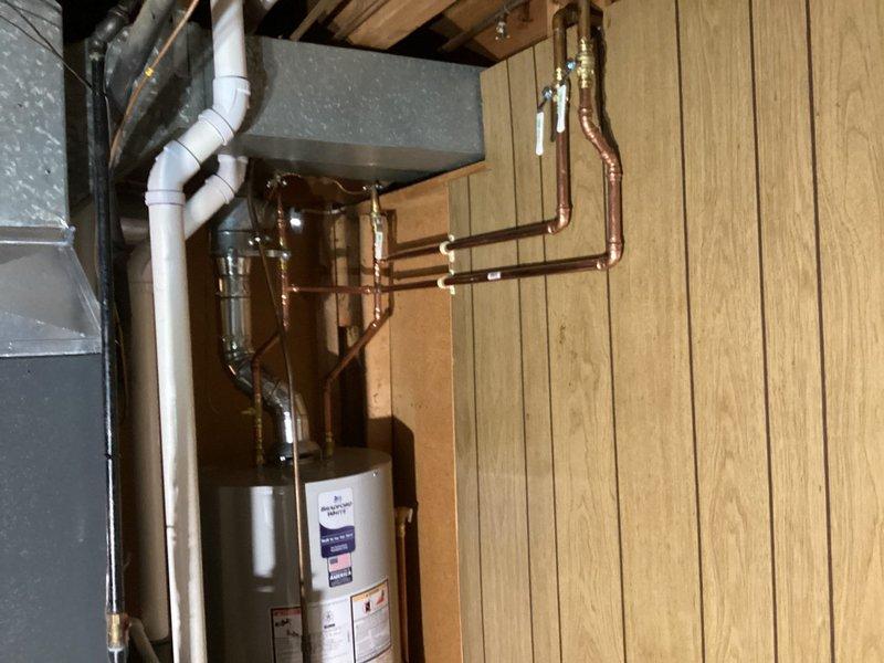 Completed installation of new residential HVAC system including furnace, air conditioning unit, and water heater in customer's utility room. New water heater was properly connected with copper piping for inlet/outlet lines and all necessary valves. All components were installed according to manufacturer specifications with proper connections to existing ductwork and plumbing systems.