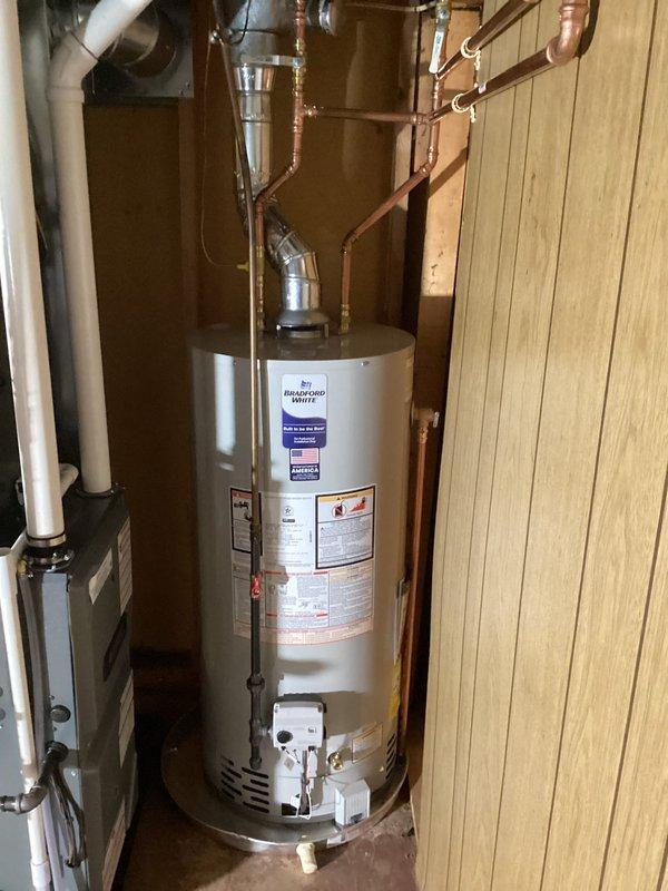 Completed installation of new residential HVAC system including furnace, air conditioning unit, and water heater in customer's utility room. New water heater was properly connected with copper piping for inlet/outlet lines and all necessary valves. All components were installed according to manufacturer specifications with proper connections to existing ductwork and plumbing systems.